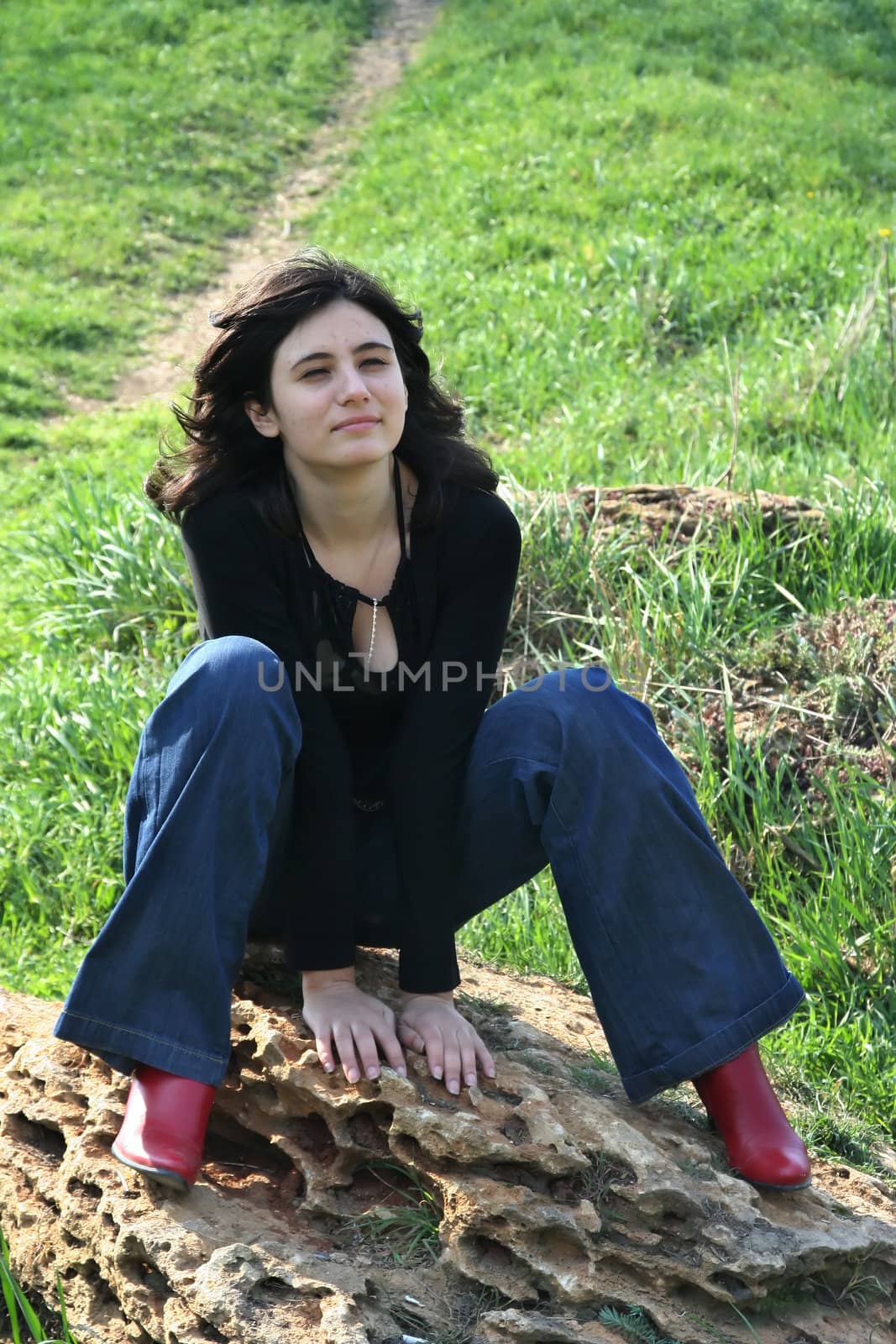 The cheerful girl sits on a stone