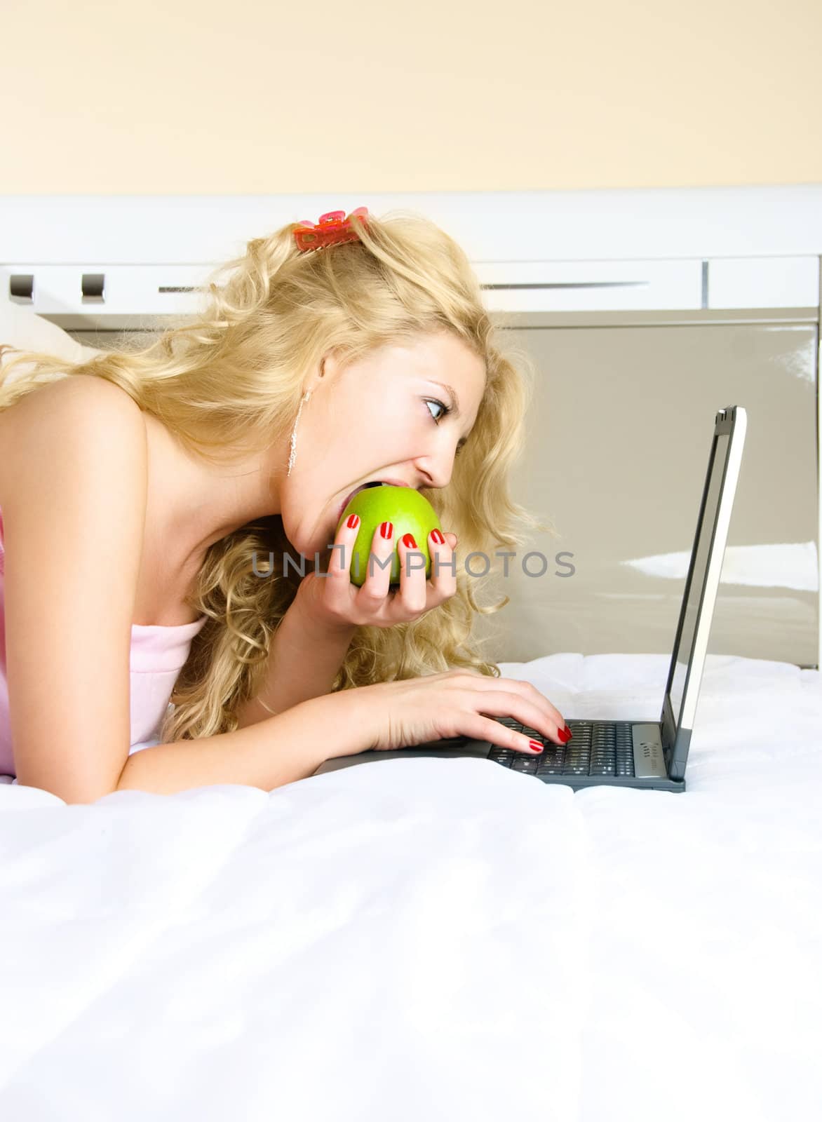 pretty girl eating an apple and using a laptop by lanak