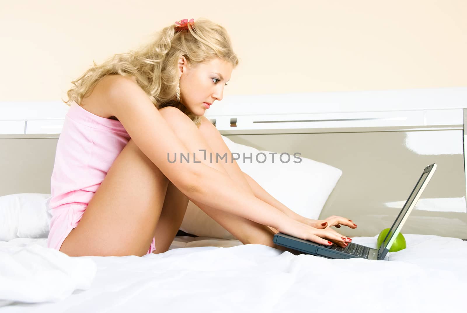 beautiful young blond woman with a laptop at home in bed