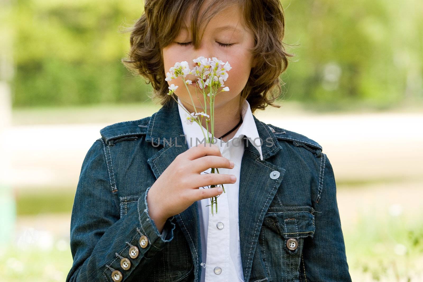 young boy is smelling on his flower