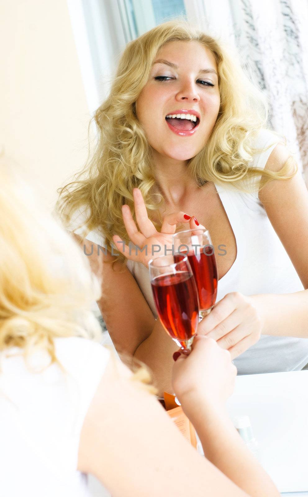 pretty woman sitting at home by the mirror, drinking wine and showing the sign OK with her fingers