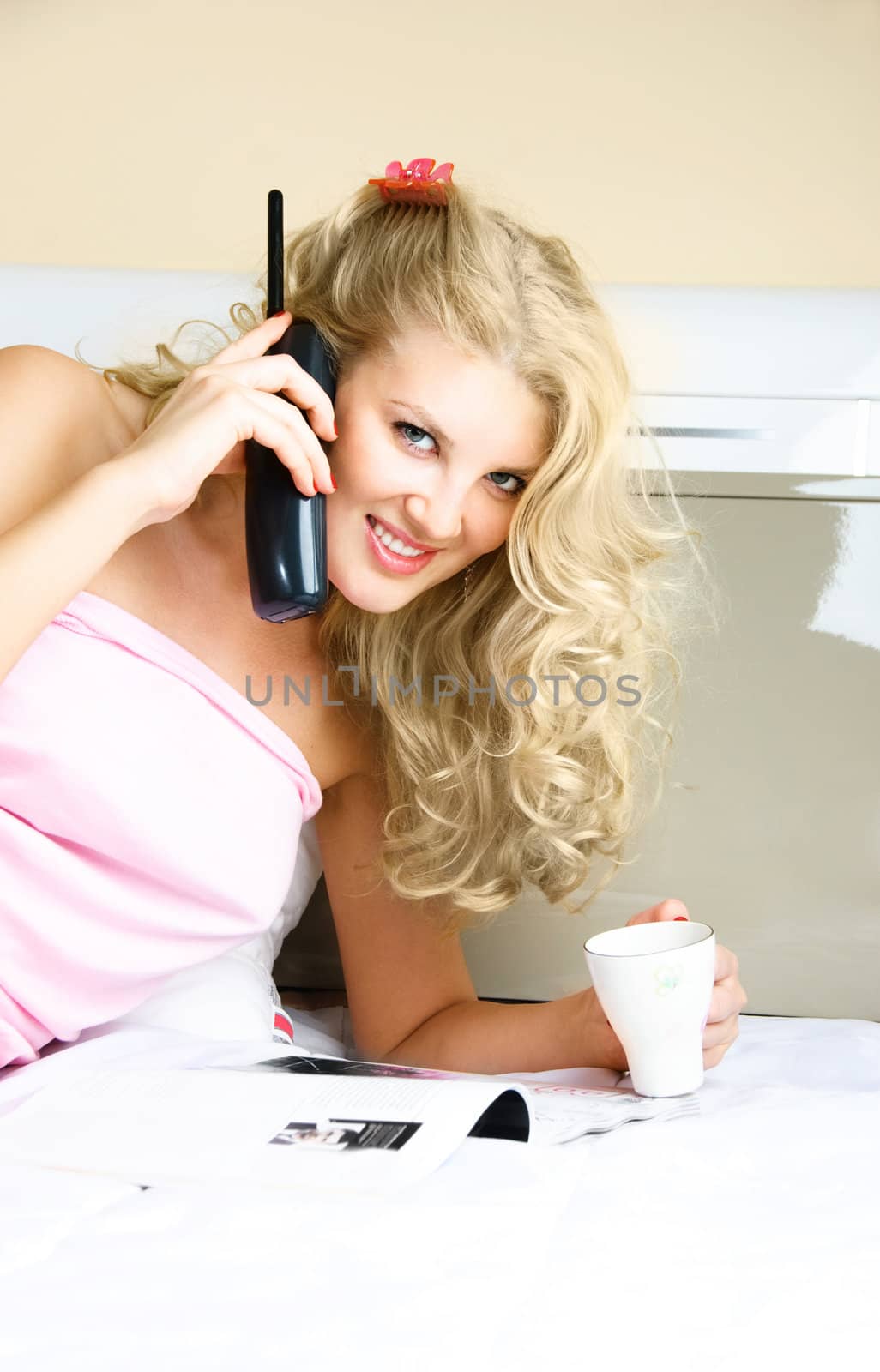 beautiful young blond woman talking on the phone and drinking coffee