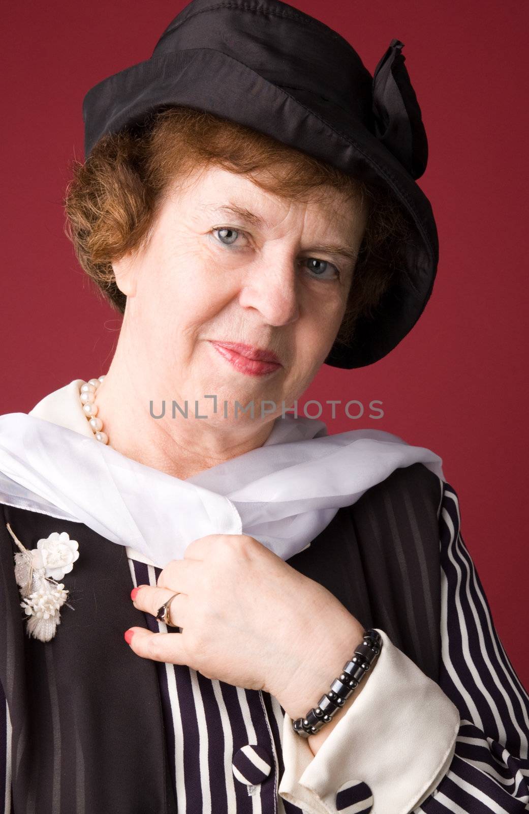 The elderly woman in a hat on a red background.
