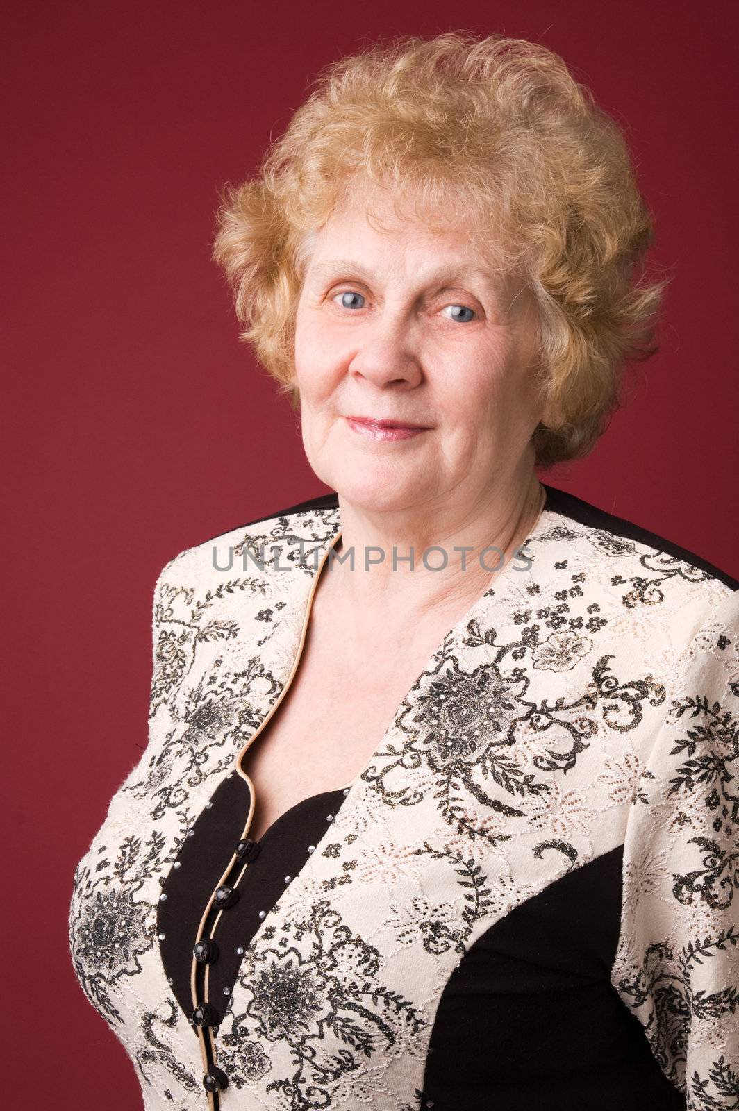 The cheerful elderly woman on a grey background.