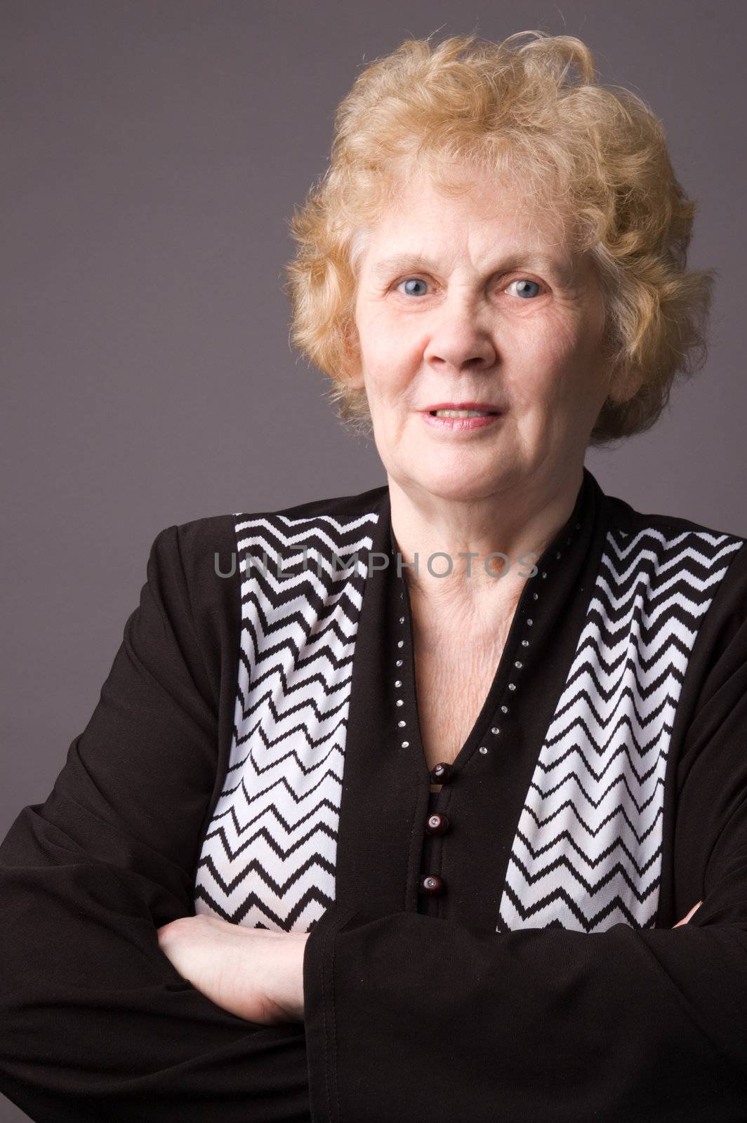 The elderly woman in a black dress on a grey background.