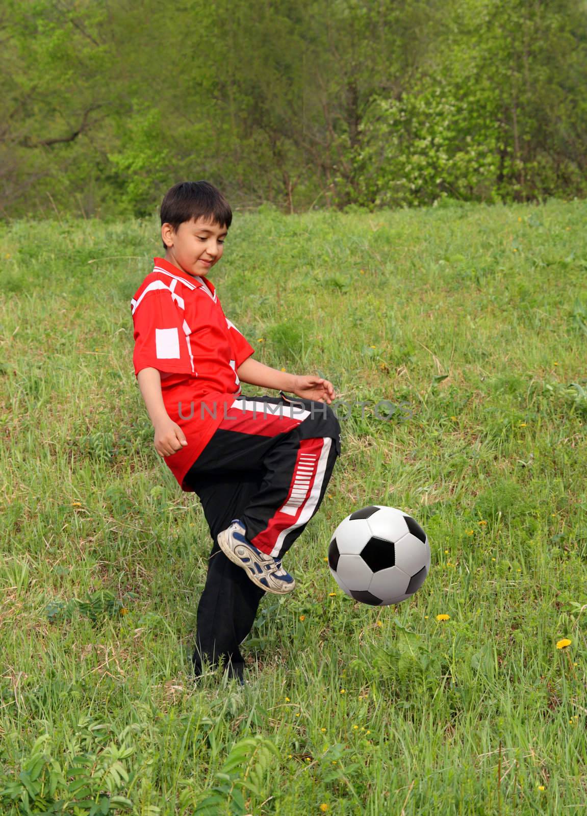 asian boy playing football on green grass