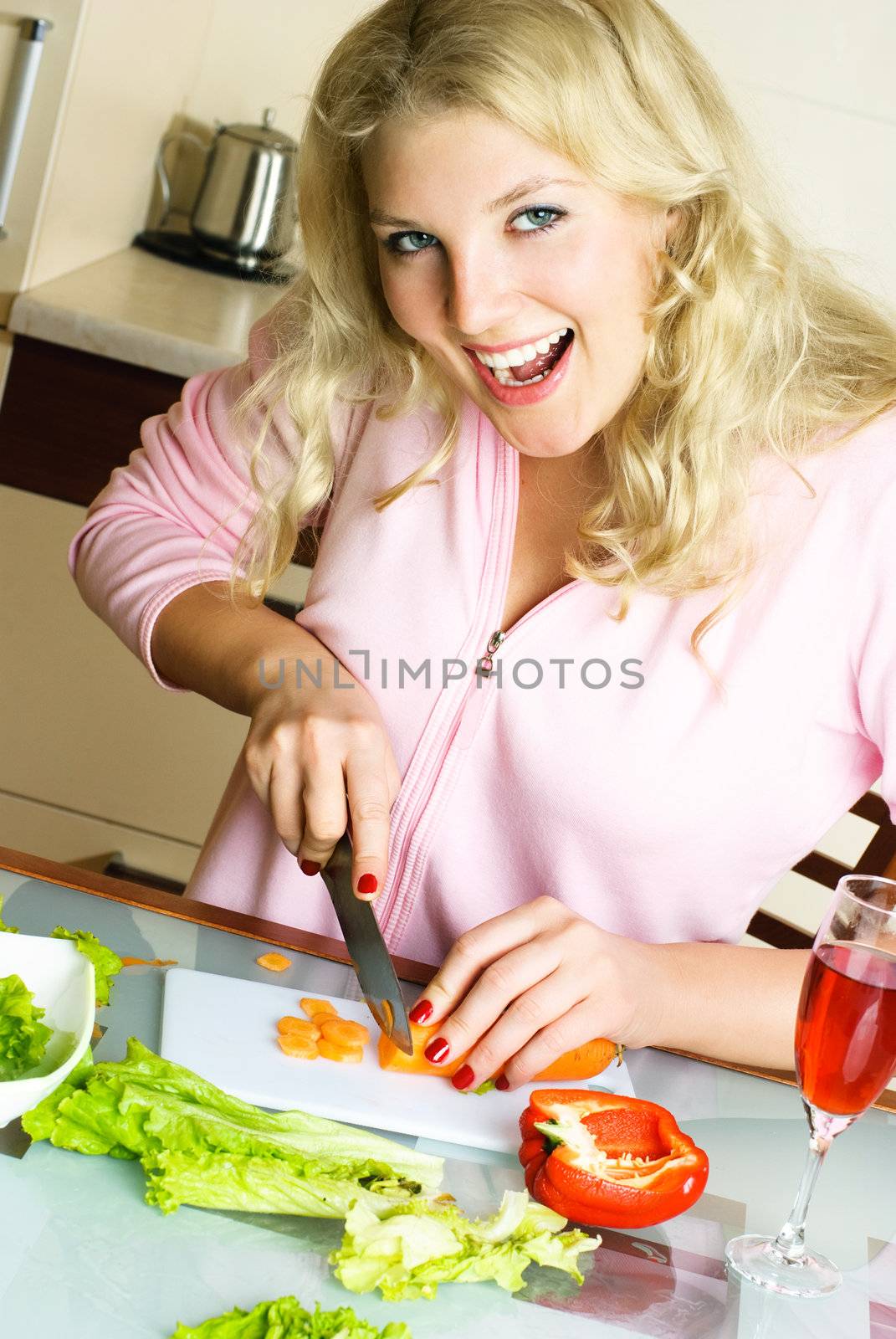 excited young woman making salad and cutting carrot at home in the kitchen