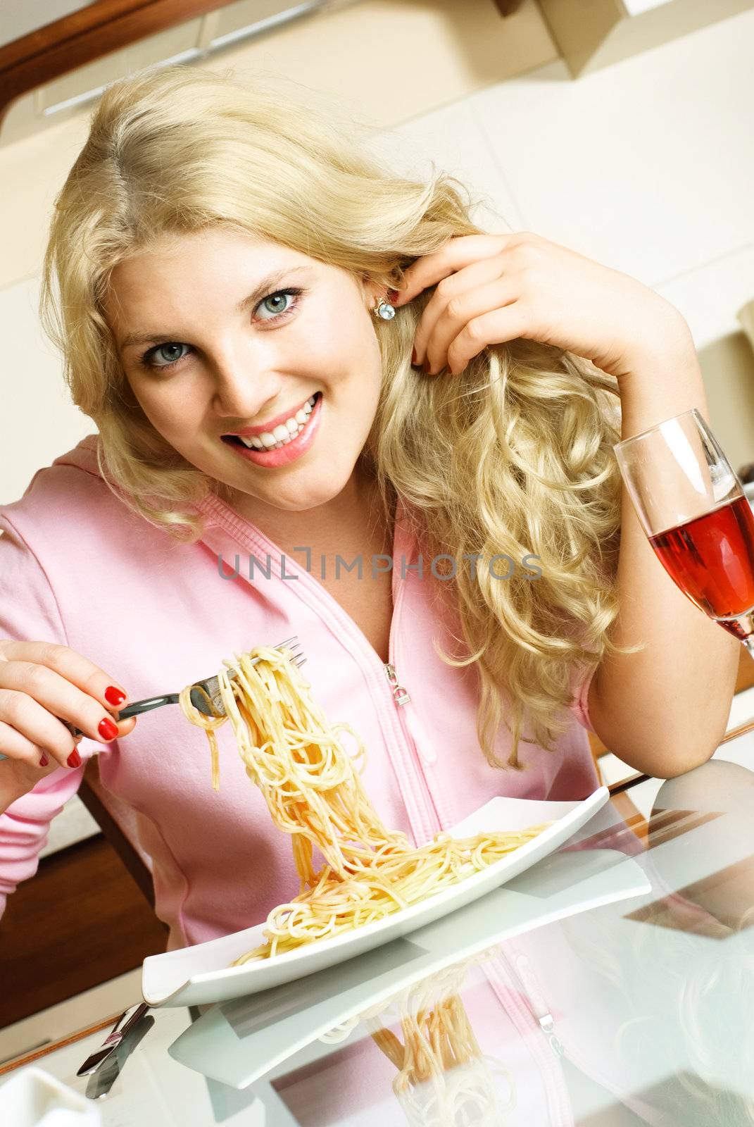 happy laughing beautiful woman at home in the kitchen eating spaghetti