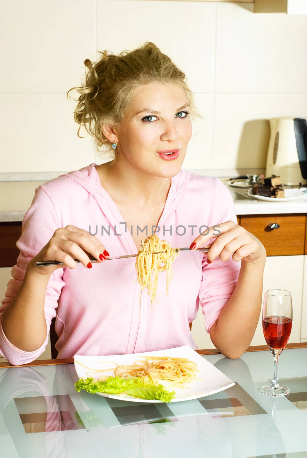 happy beautiful woman at home in the kitchen eating spaghetti