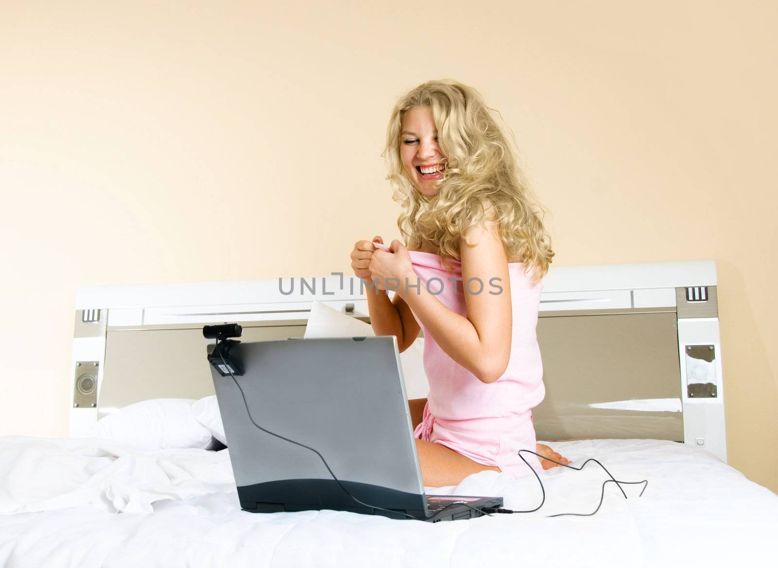pretty blond woman communicating with her friend using a web camera and laughing