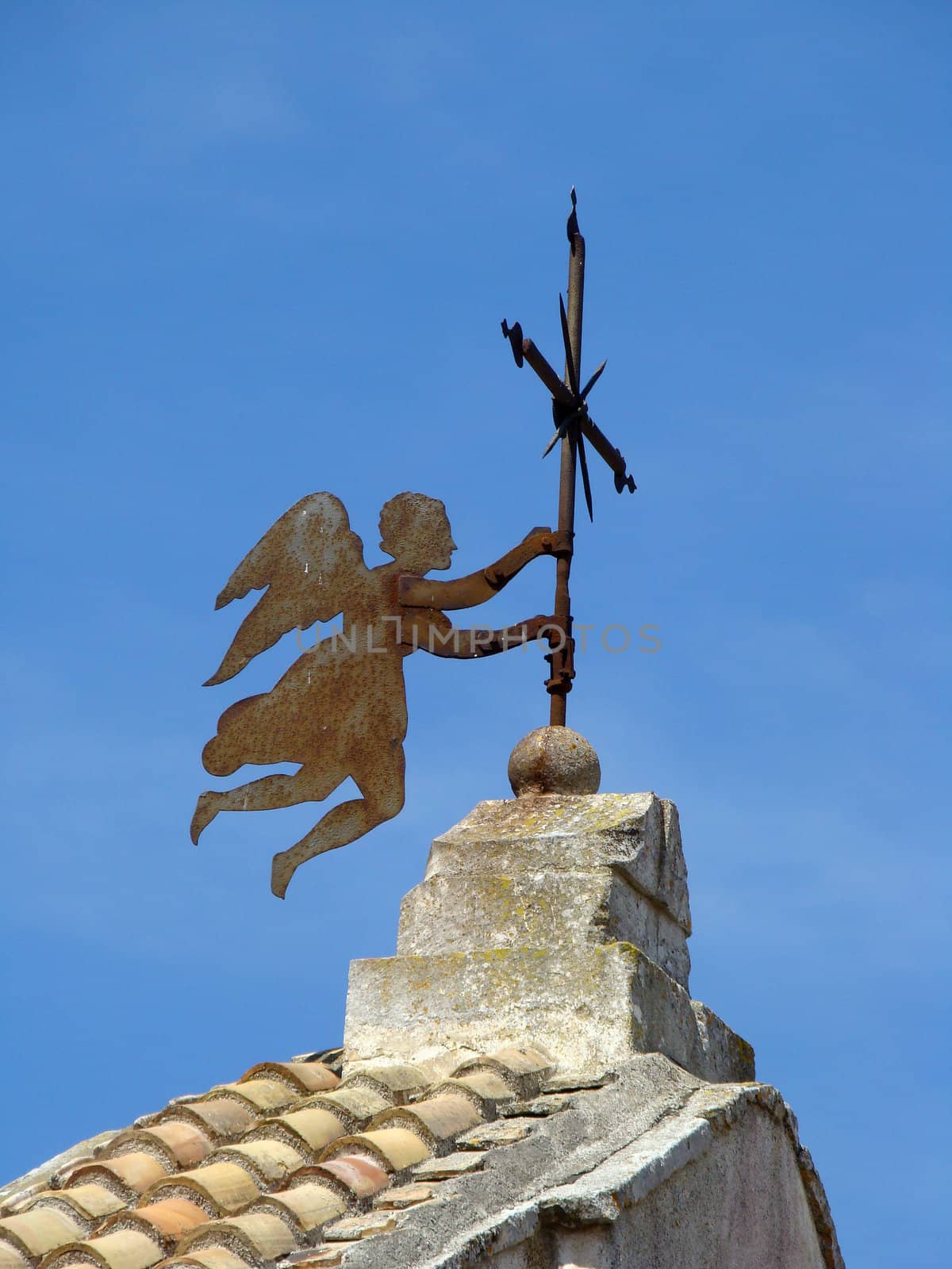 
angel holding cross on roof of the church in small town in Apulia in Italy.