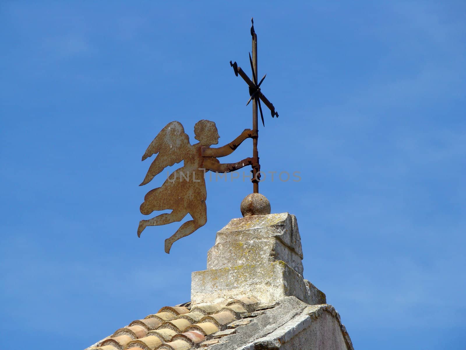 angel holding cross on roof of the church in small town in Apulia region in Italy.