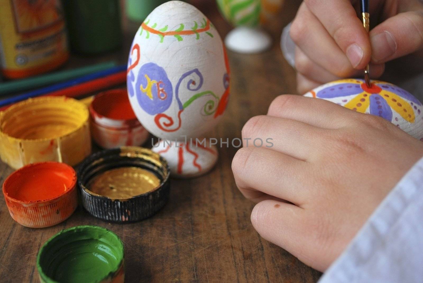 the girl enterring wooden egg, hands with paints