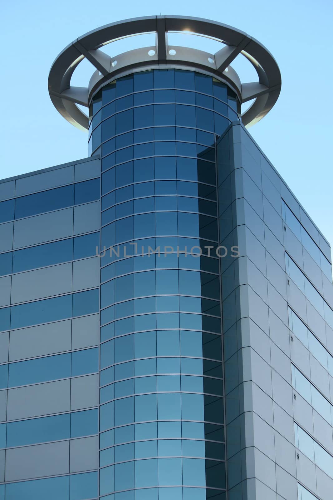 a modern city building, showing many windows, against a blue sky
