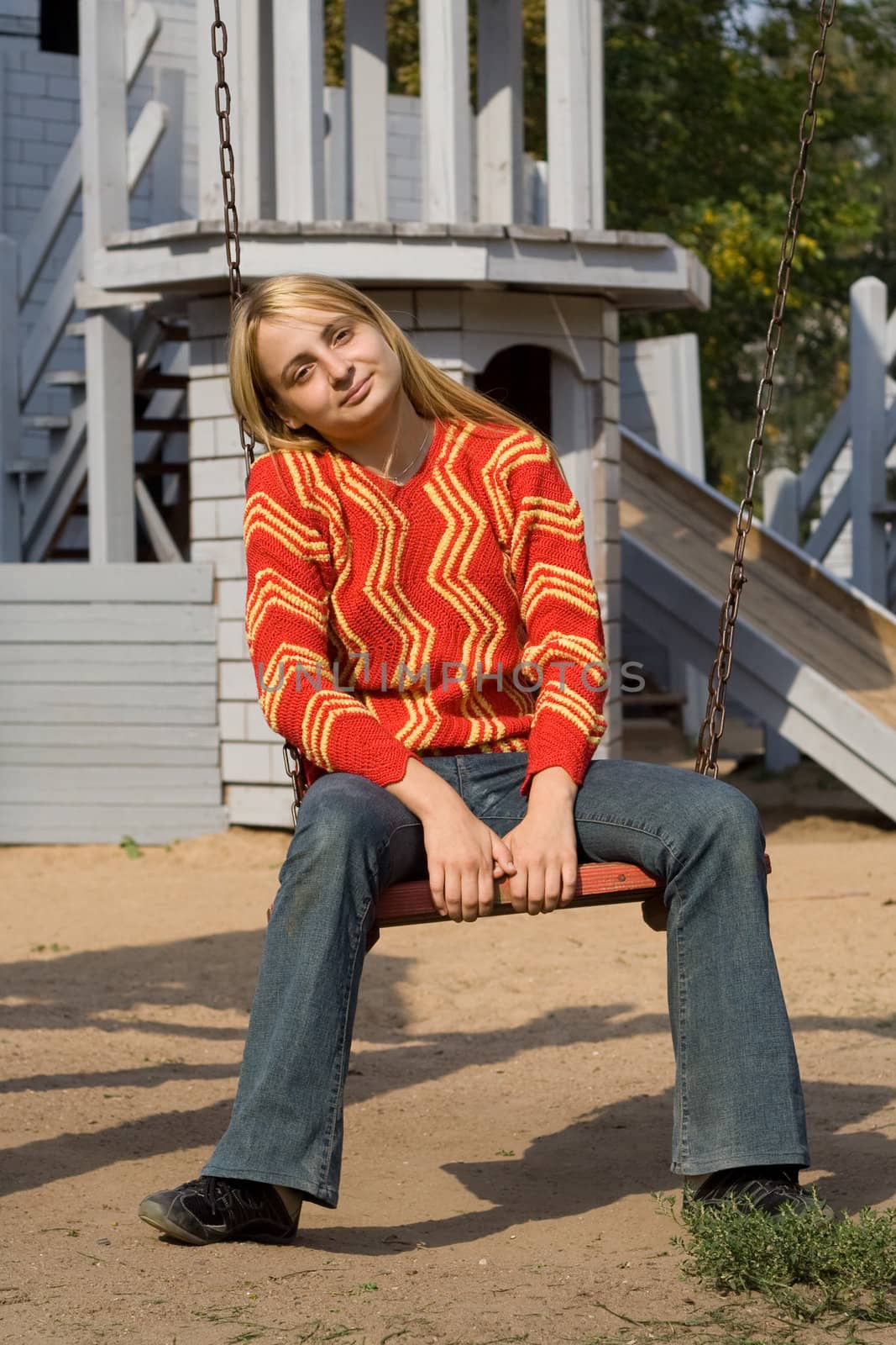 Girl in red pullover sitting on swing
