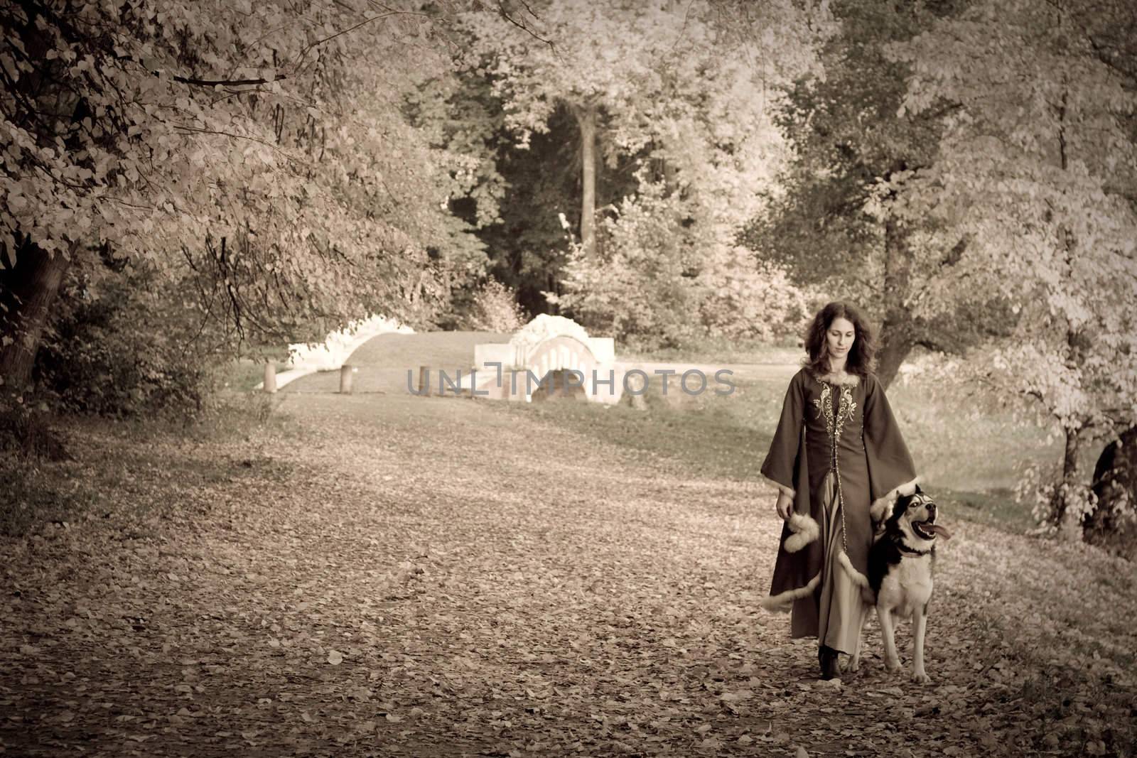 Lady in medieval dress and dog in the forest
