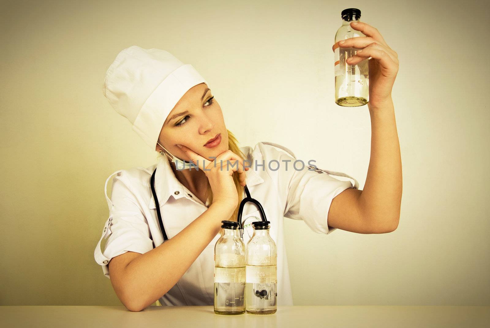 portrait of a beautiful young doctor with a stethoscope and medications sitting by the table in her office 