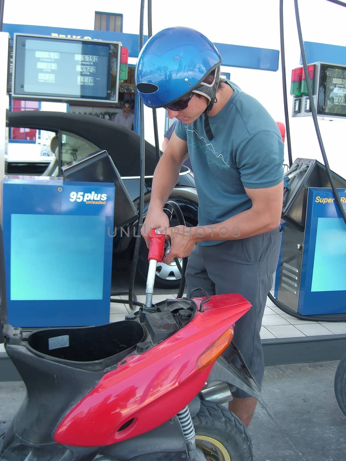 a young man is filling his scooter with fuel at the gas station