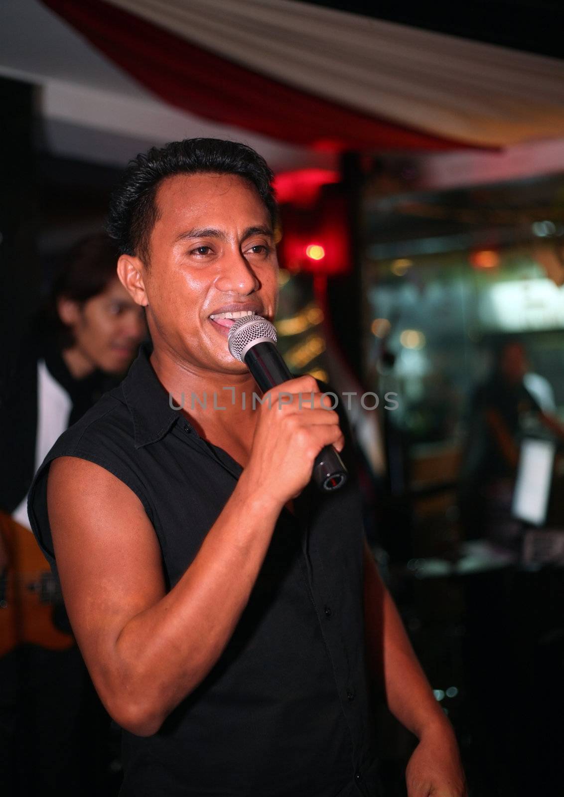 Smiling musician at an alive concert in a night club "La vida loka". Bali. Indonesia