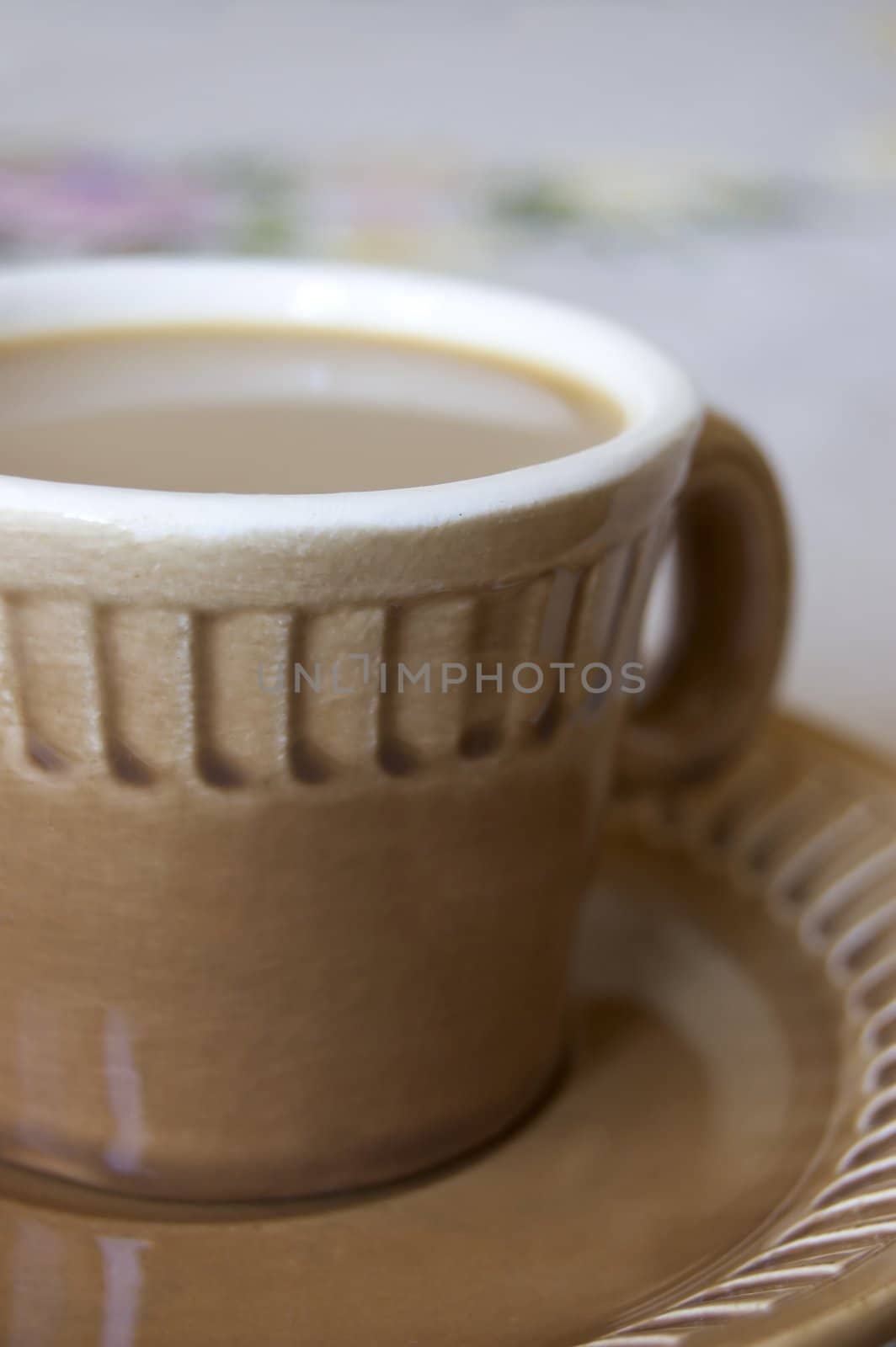 Cup from coffee on the table covered with a cloth embroidered colours.