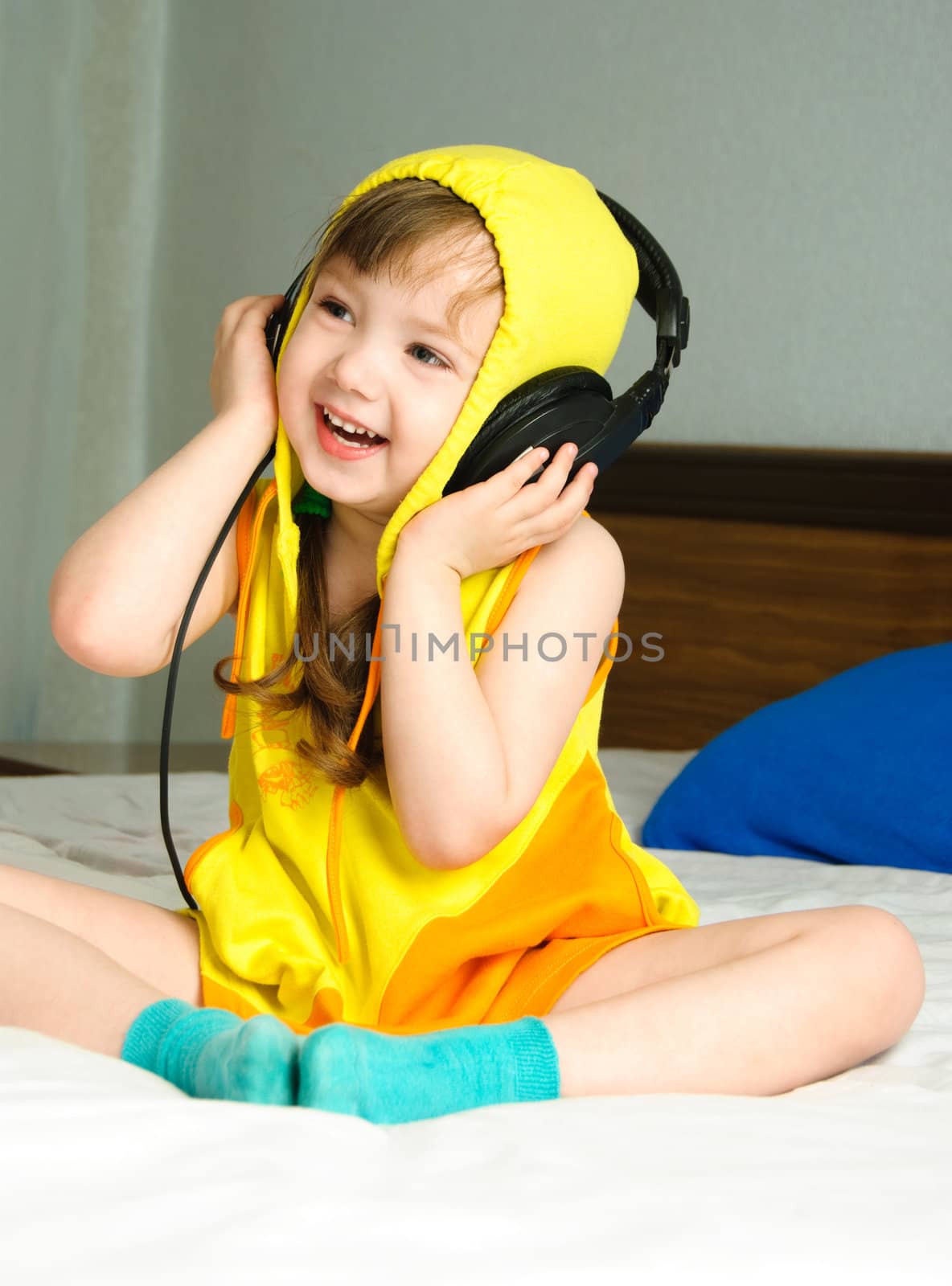 cute little girl sitting on the bed and listening to the music
