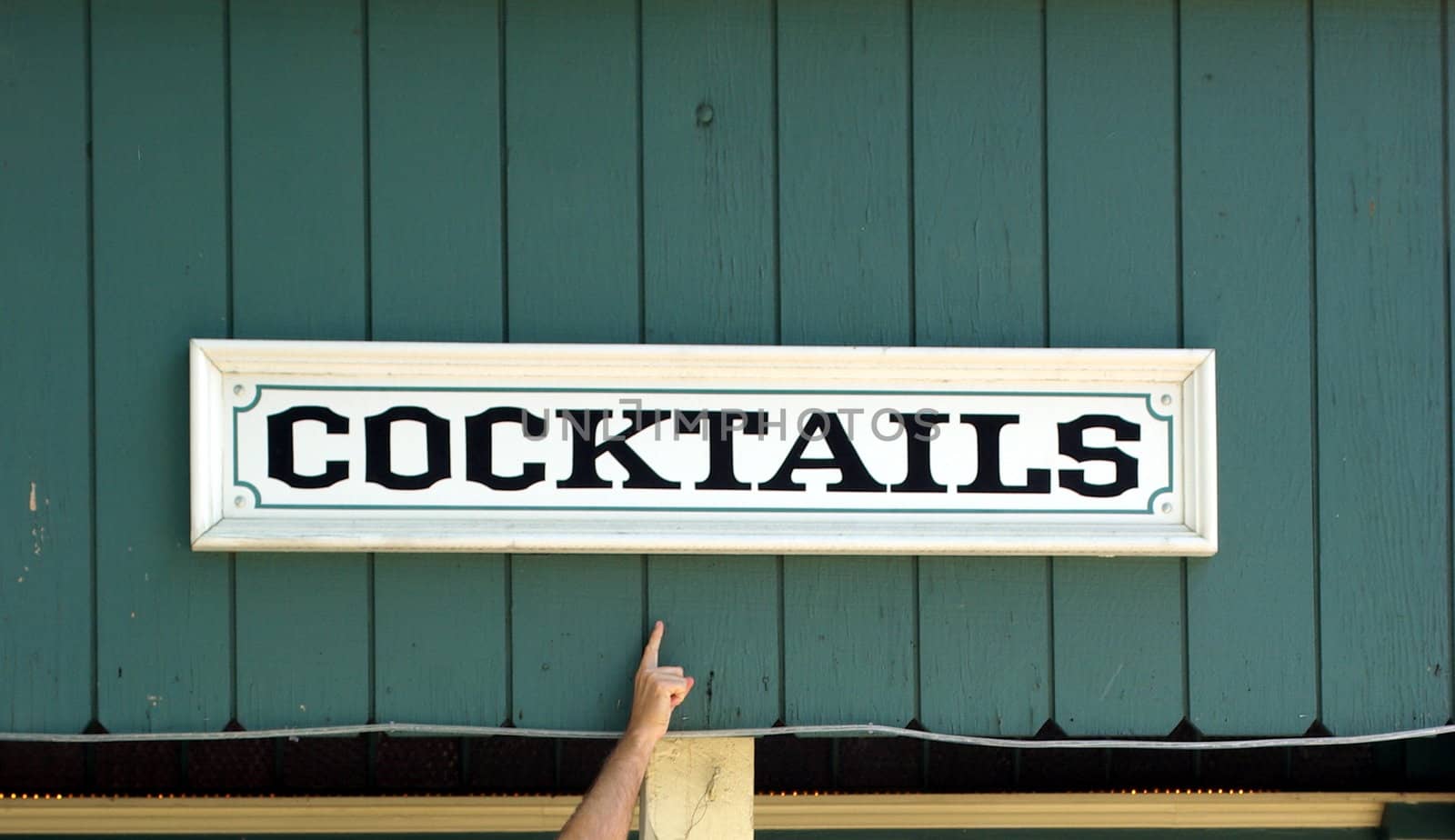 A cocktail sign on an old wooden building with a finger pointing to it.