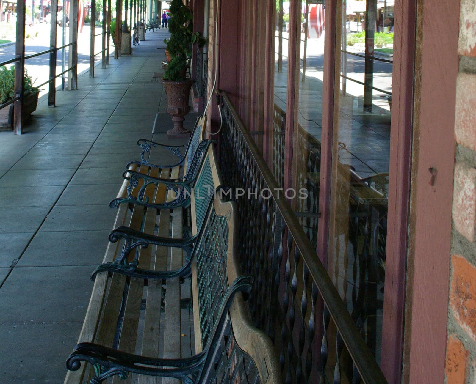 A covered walkway in front of local shops in a small town.
