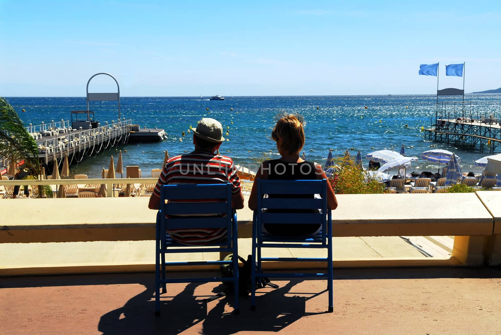 Couple relaxing in chairs on Croisette promenade in Cannes, France