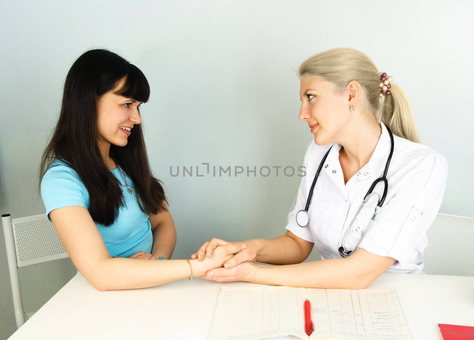 doctor sitting by the table and consulting a patient in her office
