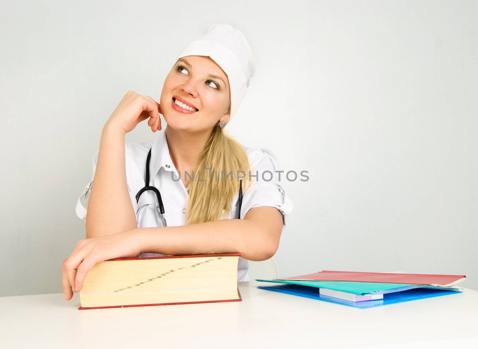 portrait of a young beautiful thoughtful doctor sitting by the table in her office