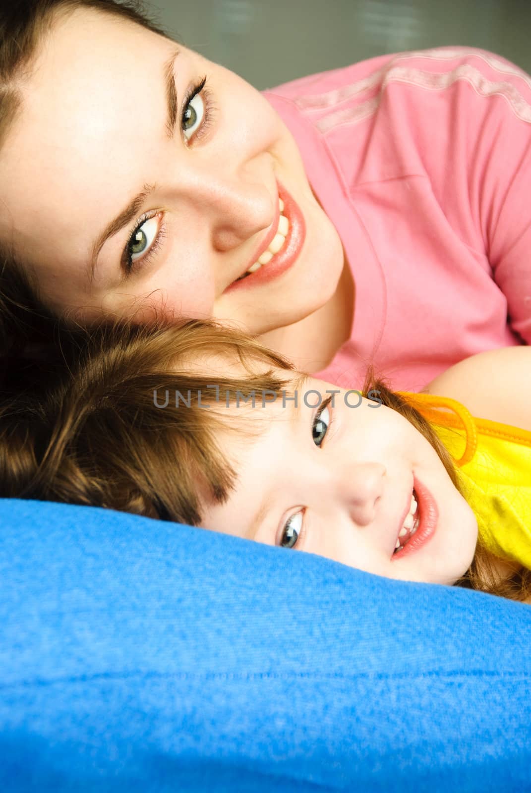 young beautiful mother and her little daughter in bed at home