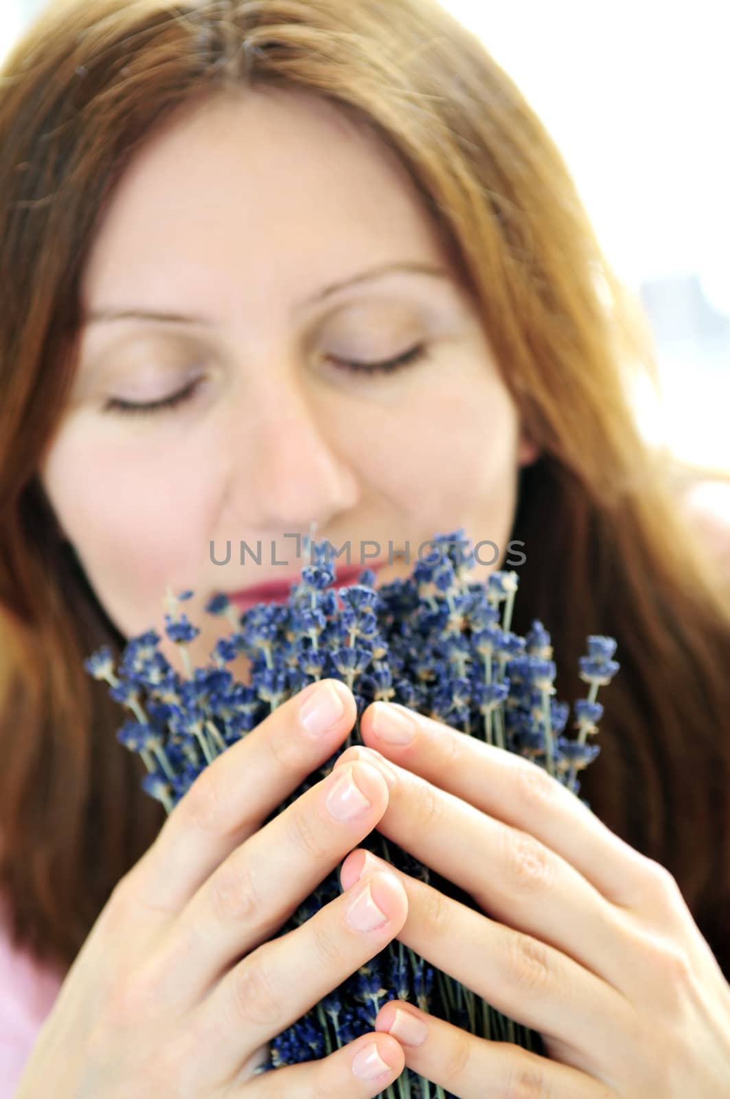 Mature woman smelling lavender flowers - focus on hands