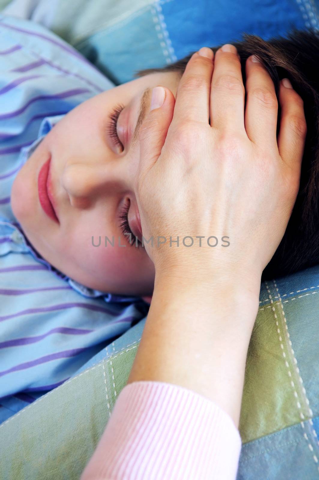 Mother's hand feeling the forehead of a sick child