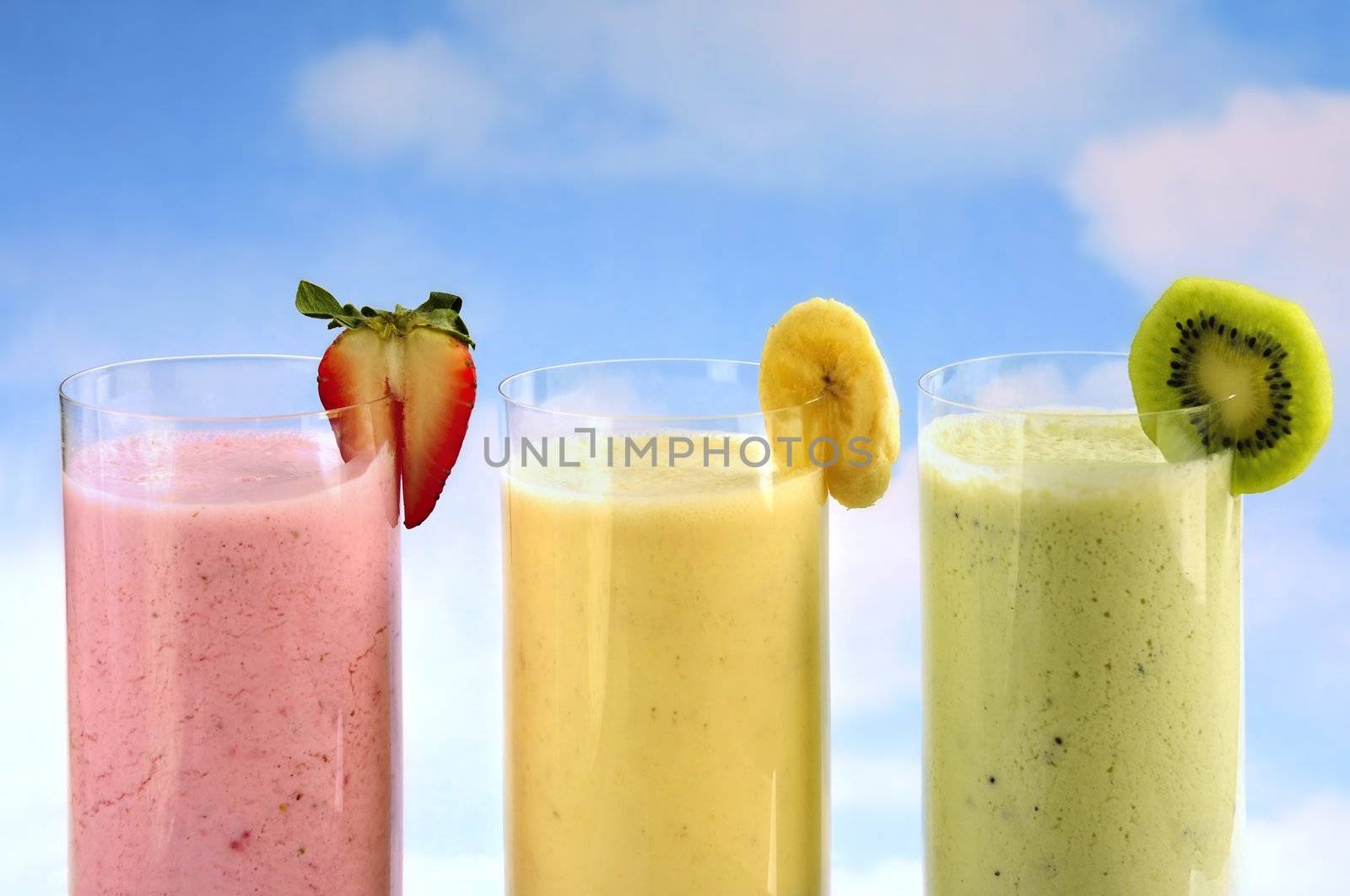 Assorted fruit and berry smoothies on blue sky background