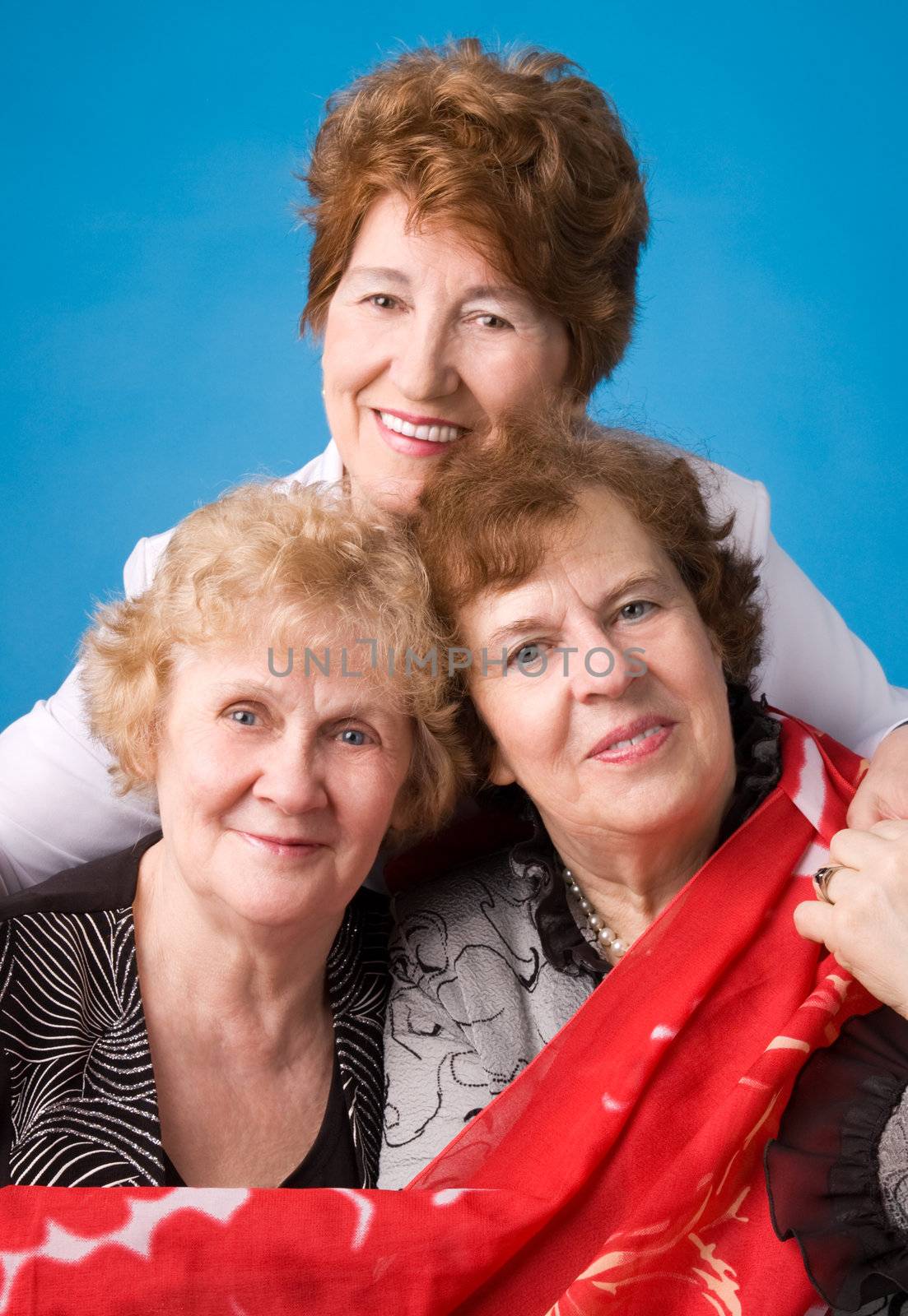 A portrait of three cheerful elderly women on a dark blue background.
