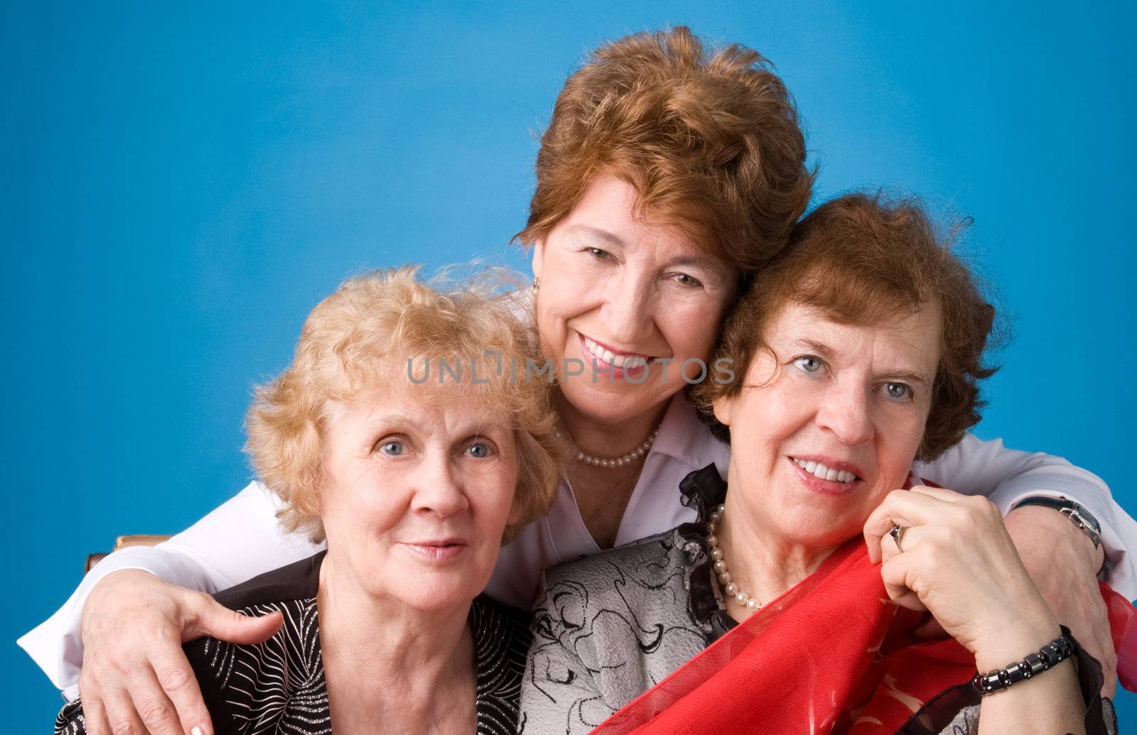 A portrait of three cheerful elderly women on a dark blue background.