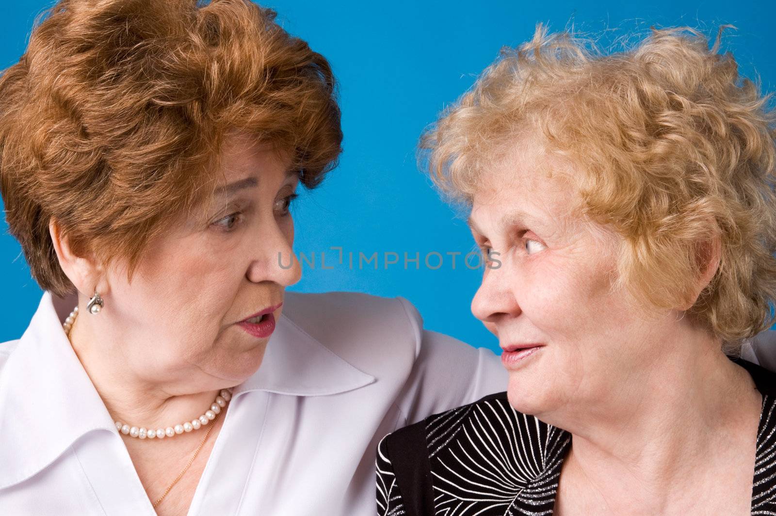 A portrait of two cheerful elderly women on a dark blue background.