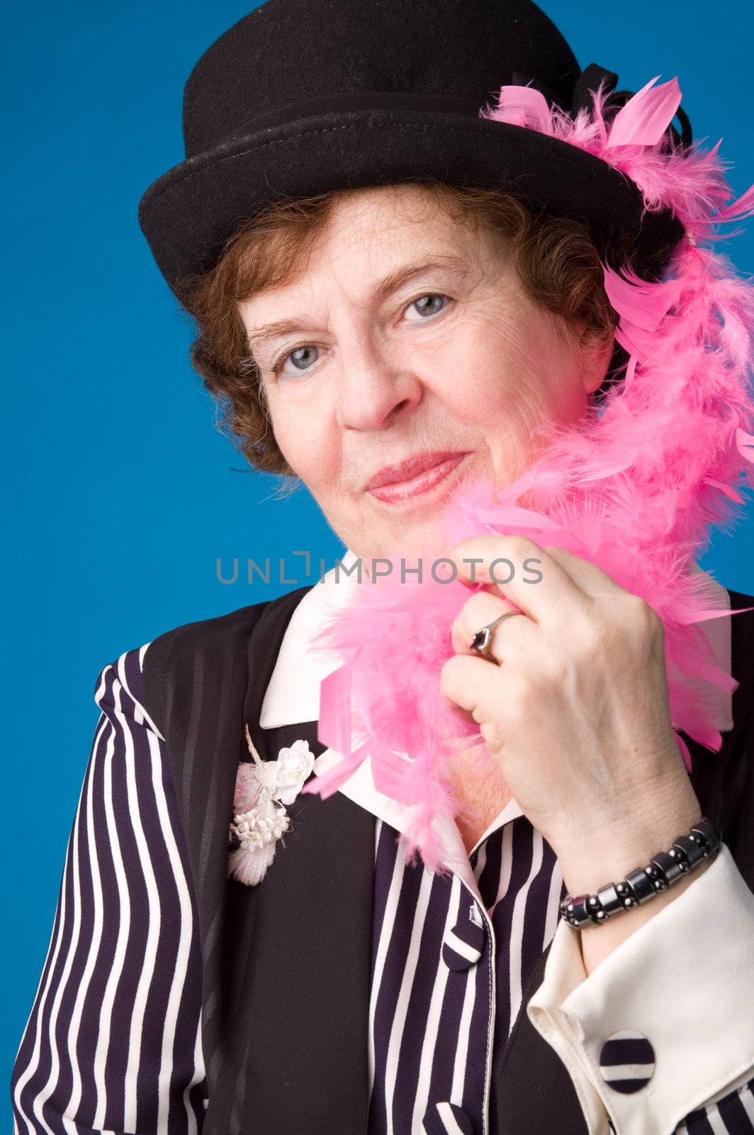 The cheerful elderly woman in black hat on a blue background.