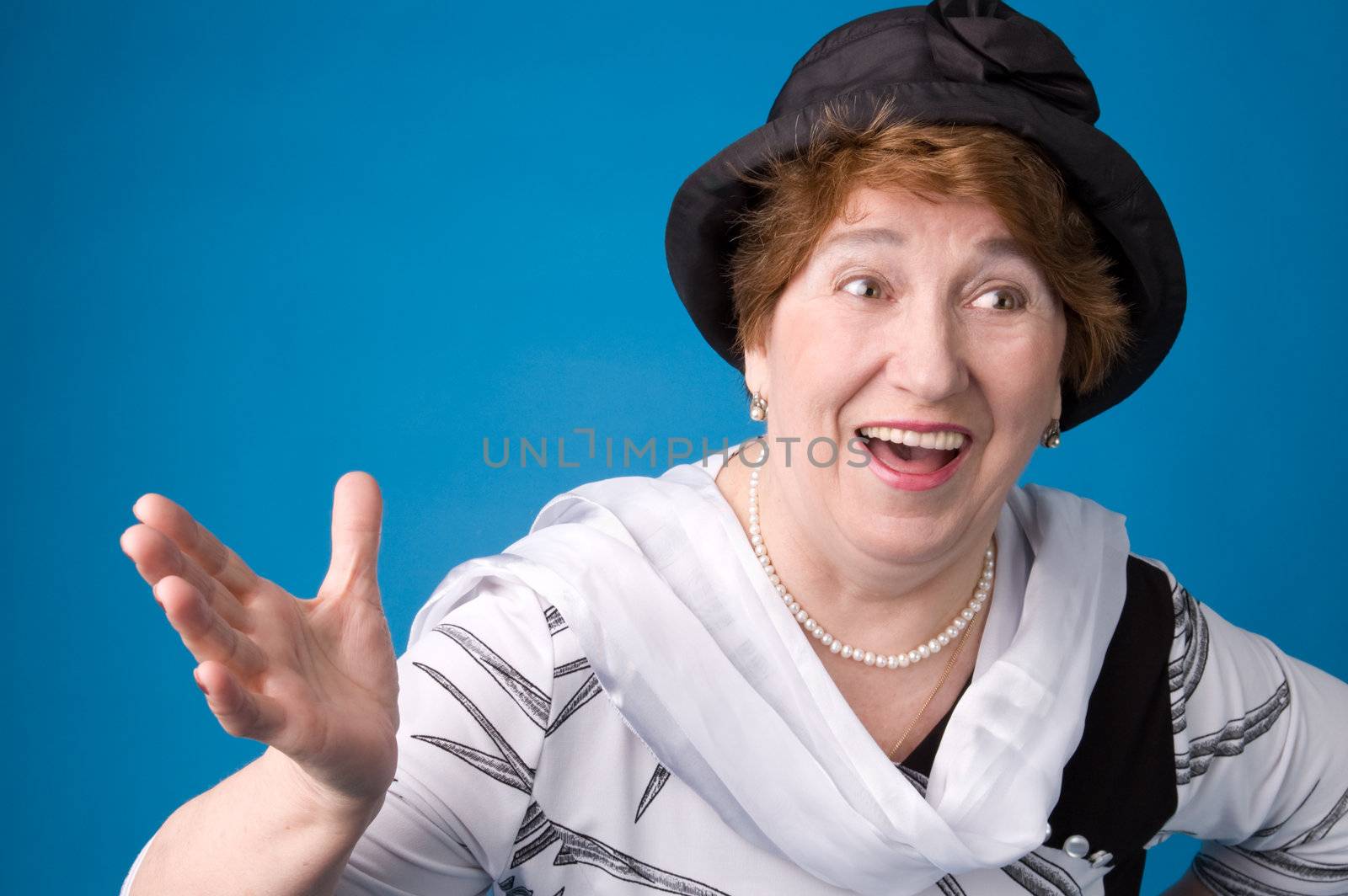 The cheerful elderly woman in a white dress on a blue background.