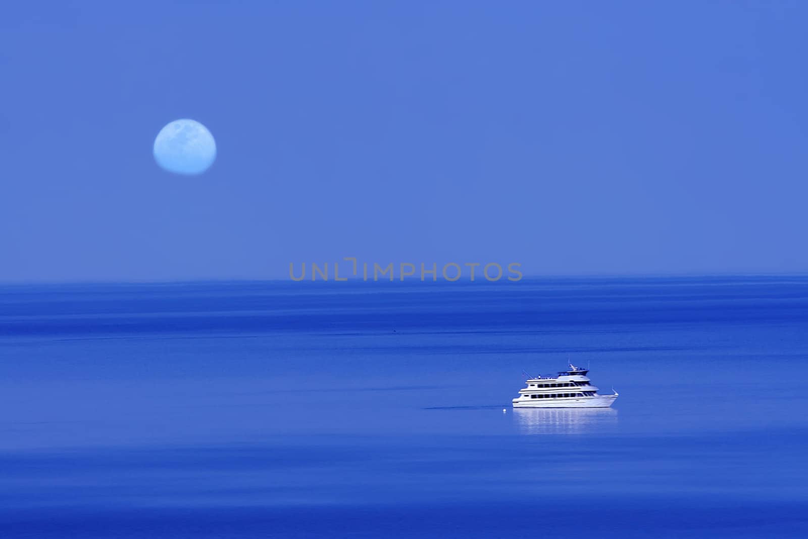 Moon over blue lake with boat