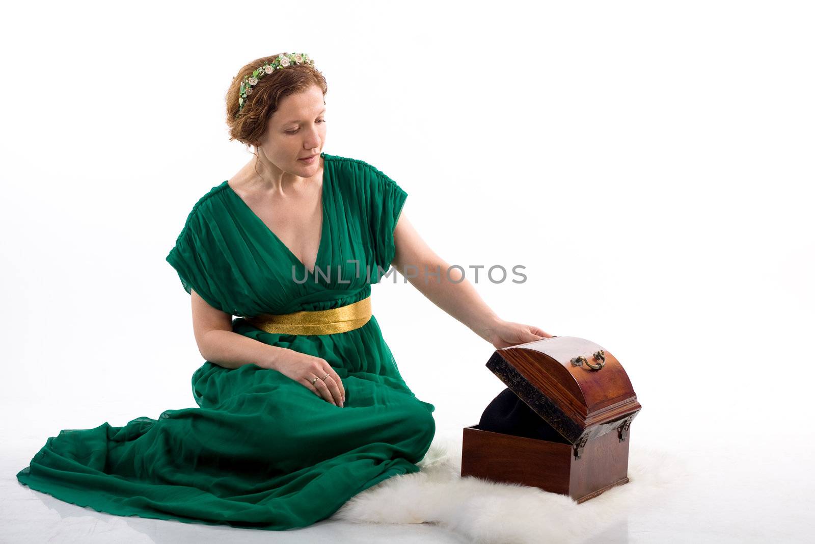Lady in green antique dress opening box on white background

