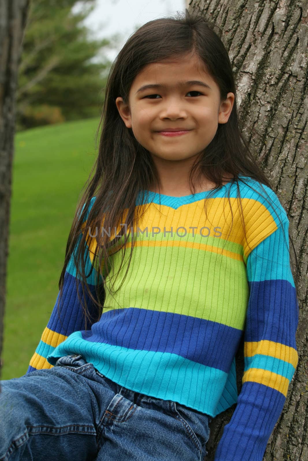 Adorable little girl leaning up against tree