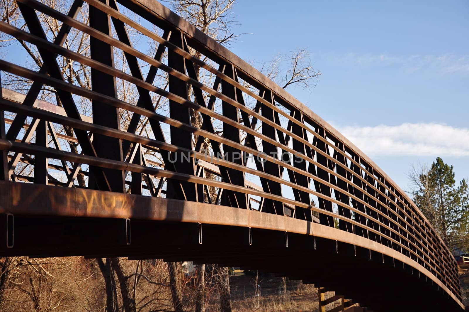 A metal bridge extends across a stream in rural Colorado.