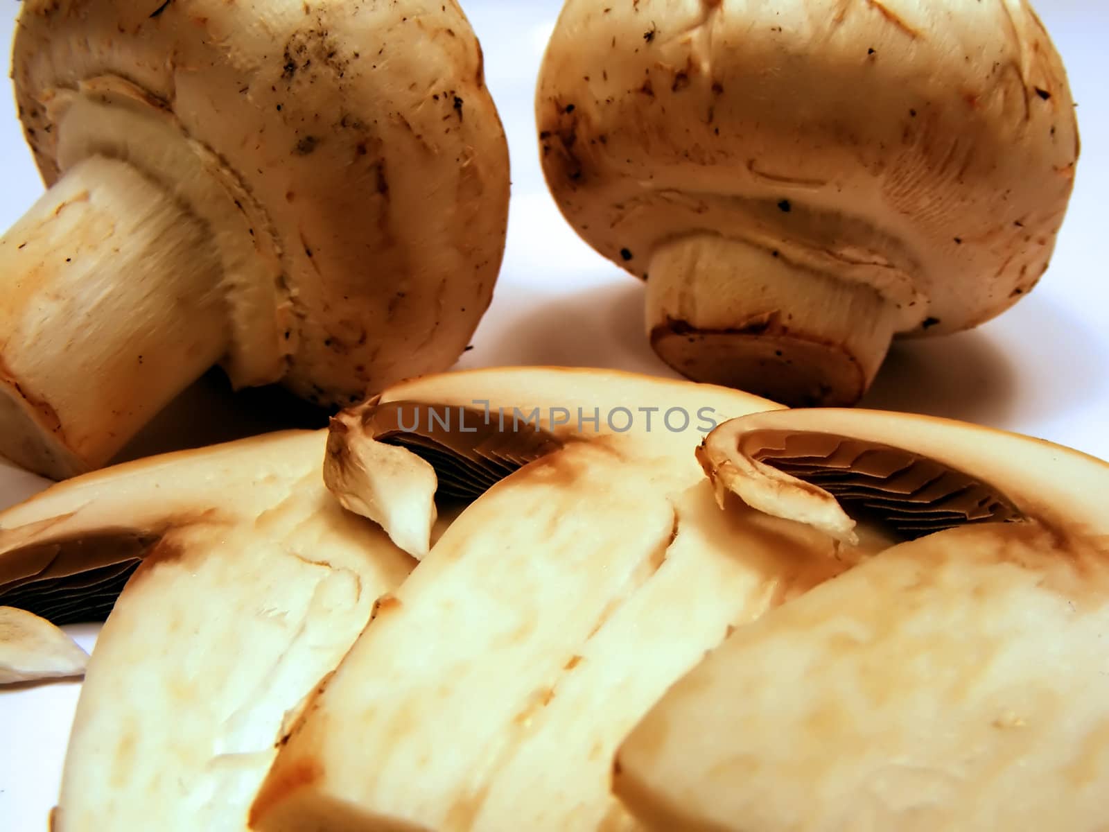 Organic grocery store mushrooms sliced and whole on white background.