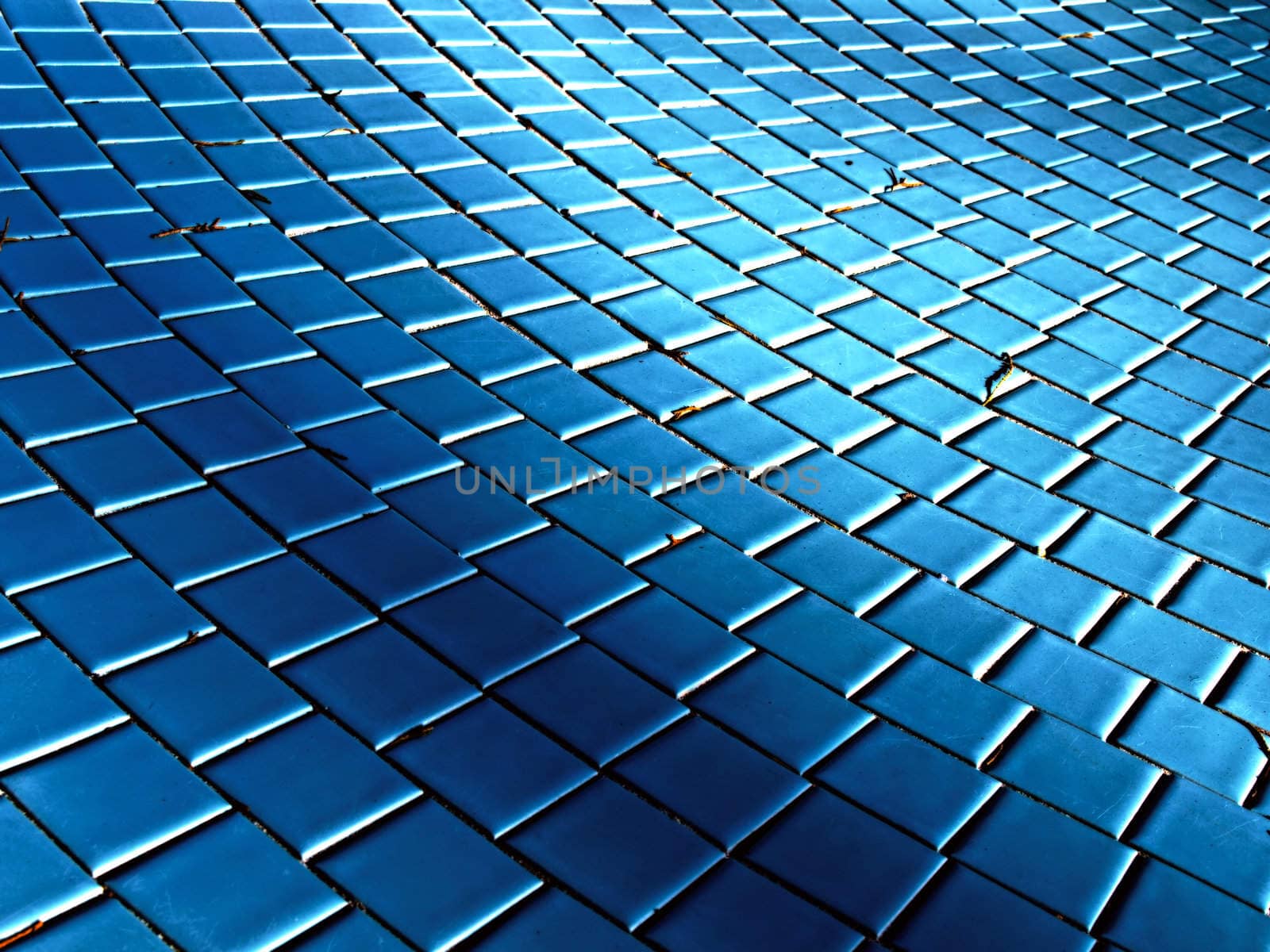 A wave effect created by light and shadow on the tile of a drained pool.