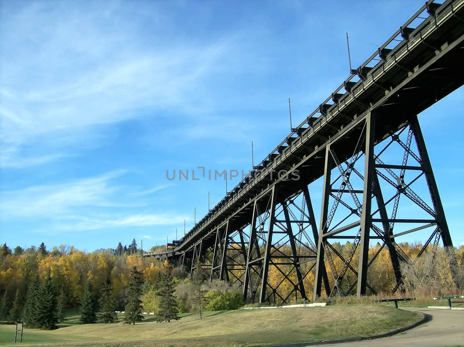 Historic train bridge spanning the distance over a park in early autumn.