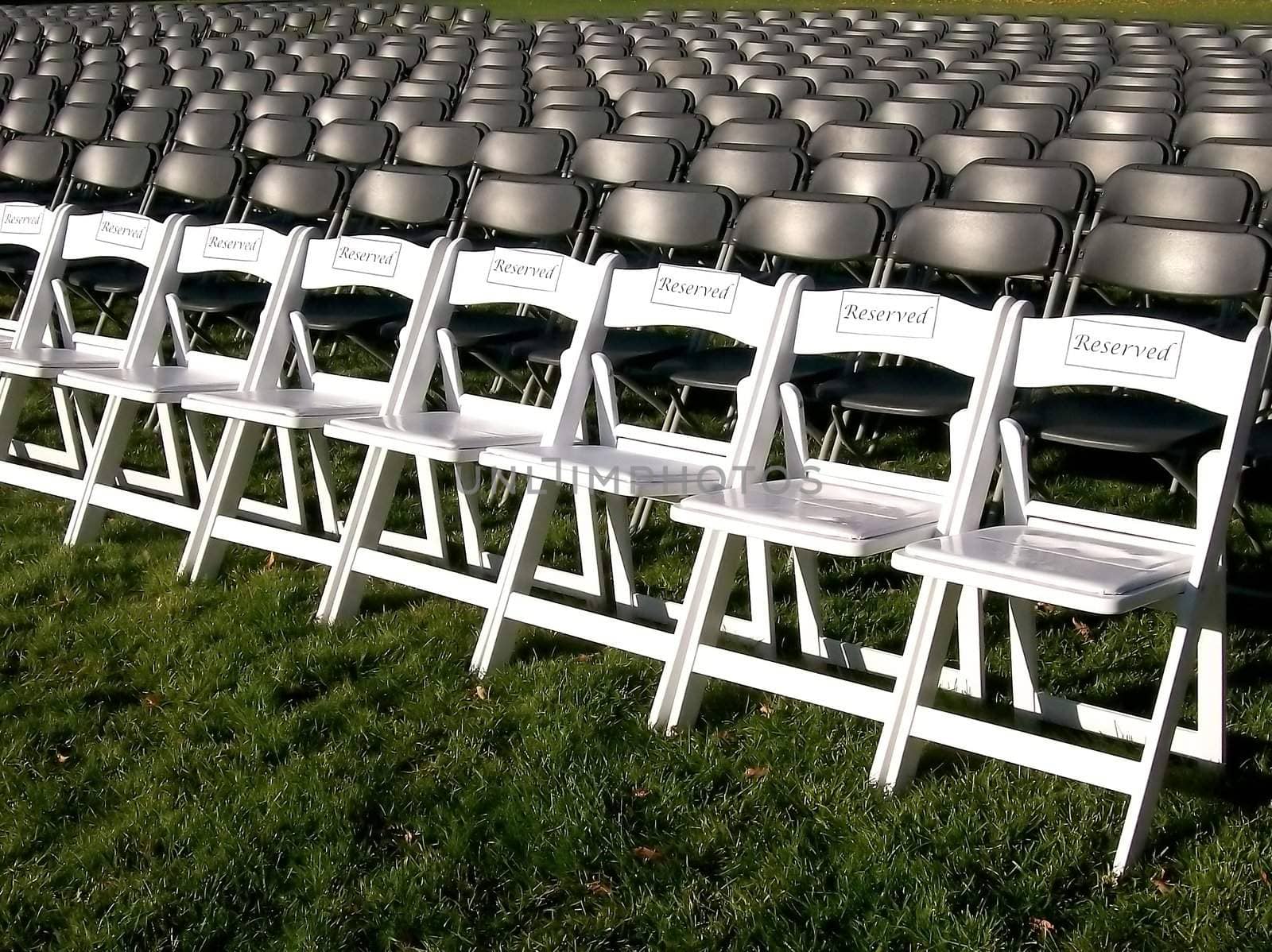 White VIP reserved chairs at an outdoor event.