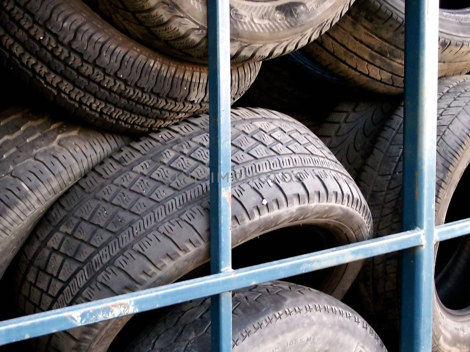 Used tires stored in a bin behind a tire repair shop.