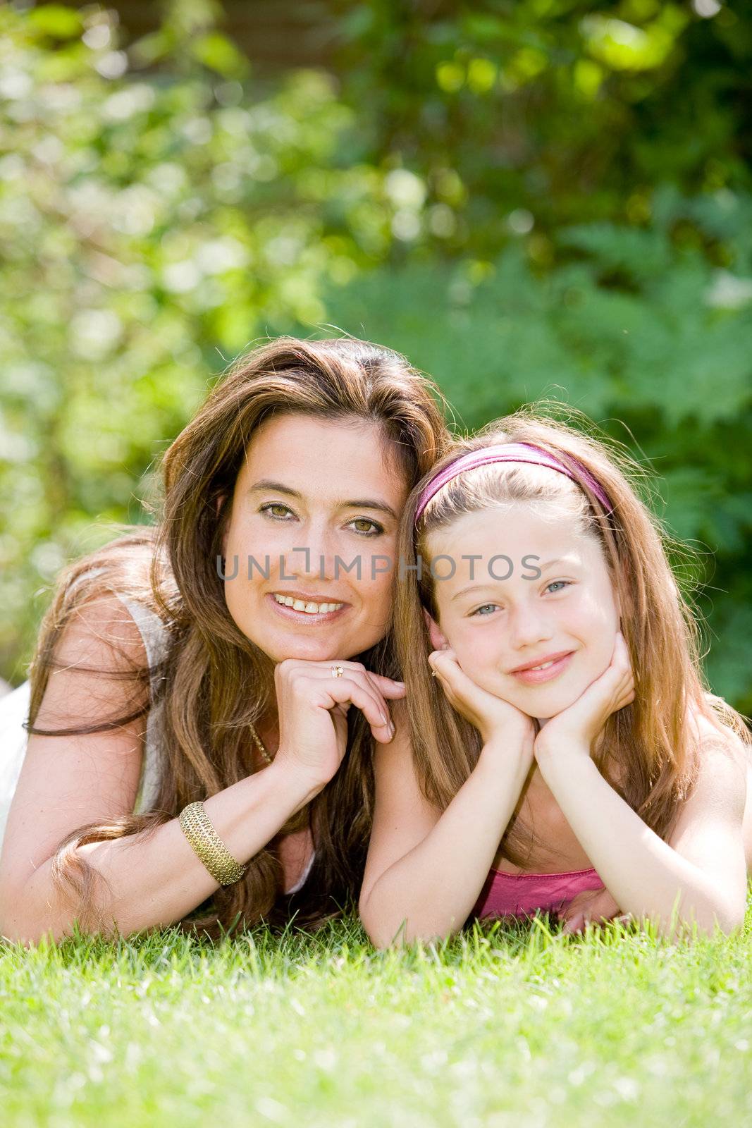 Mother and daughter lying together in the grass on a summer day