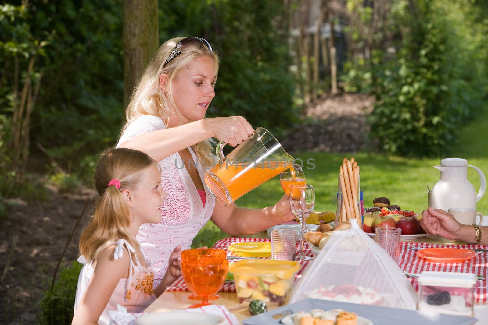 family sitting outdoors on a summer day enjoying a picknick